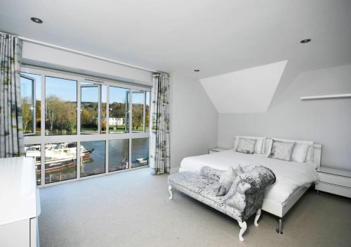 een slaapkamer met een bed, een bank en ramen bij The Oars - Riverfront Property in Henley on Thames