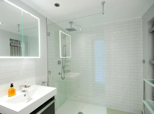 a white bathroom with a sink and a shower at The Oars - Riverfront Property in Henley on Thames