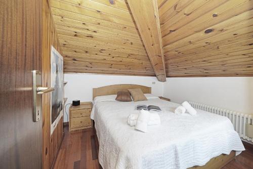 sypialnia z dużym białym łóżkiem i drewnianym sufitem w obiekcie iFlat Madonna di Campiglio Penthouse Brenta w Madonna di Campiglio