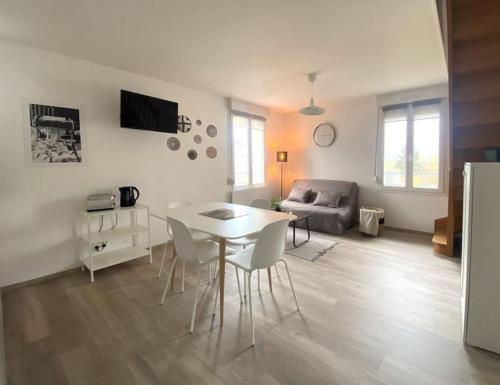 ein Wohnzimmer mit einem Tisch, Stühlen und einem Sofa in der Unterkunft Plénitude Giverny-Vernon appt 12 in Vernon