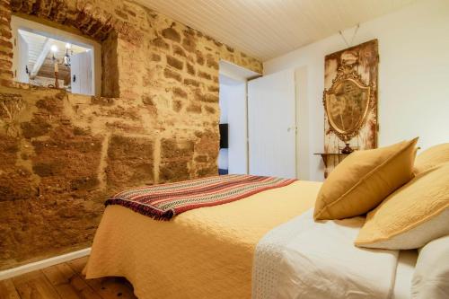 a bedroom with a bed and a brick wall at Albergue do Infante in Tomar