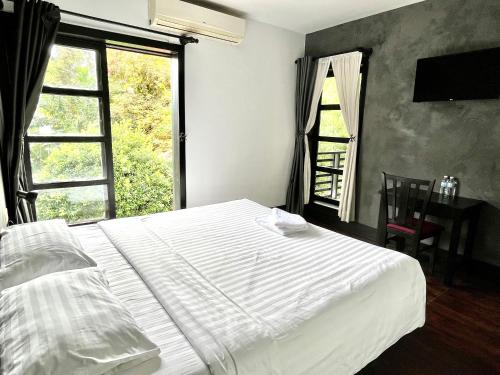 a bedroom with a white bed and a window at Prana Hotel in Siem Reap