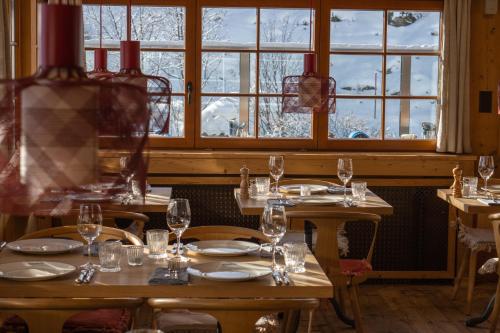 a dining room with tables and chairs and windows at Alpenblick Bergrestaurant & Hotel in Arosa
