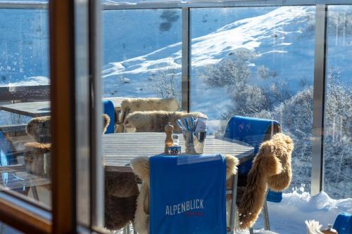 a table and chairs with snow outside a window at Alpenblick Bergrestaurant & Hotel in Arosa
