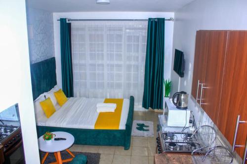 um pequeno quarto com uma cama com cortinas verdes em The Green Apartment em Ruaka