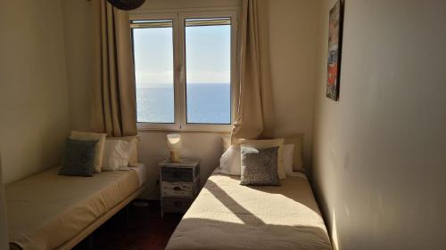 two beds in a room with a large window at The Best Atlantic Ocean View in Câmara de Lobos