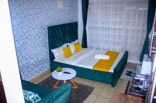 um pequeno quarto com uma cama e uma cadeira em The Green Apartment em Ruaka