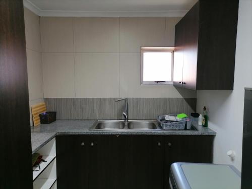 uma pequena cozinha com um lavatório e uma janela em 20 On Percy na Cidade do Cabo