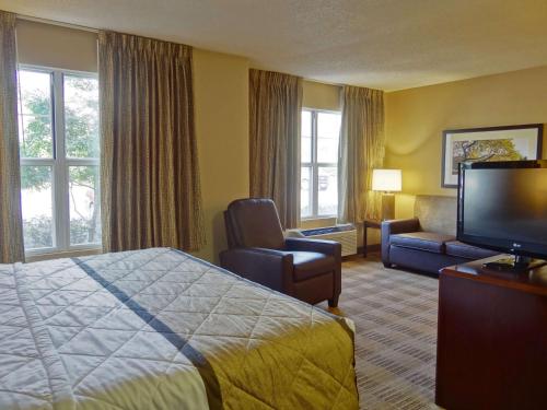 a hotel room with a bed and a flat screen tv at Extended Stay America Suites - Dallas - Plano in Plano