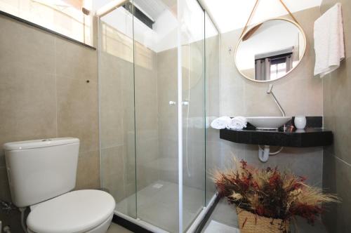 a bathroom with a shower and a toilet and a mirror at Apartamento Portal da Ferradura in Búzios