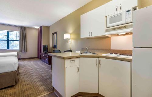 a kitchen with white cabinets and a room with a bed at Extended Stay America Select Suites - Fayetteville - Springdale in Springdale
