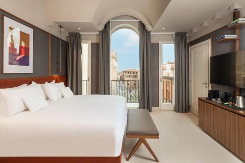a bedroom with a large white bed and a large window at Hotel Brun in Bologna