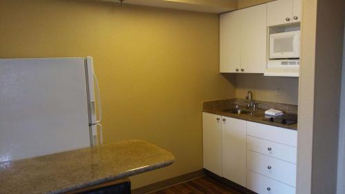 La cuisine est équipée d'un réfrigérateur blanc et de placards blancs. dans l'établissement Extended Stay America Suites - Houston - Med Ctr - NRG Park - Braeswood Blvd, à Houston