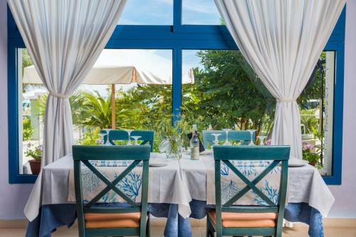 mesa de comedor con sillas azules y ventana en Hotel Eliseo, en Bellaria-Igea Marina