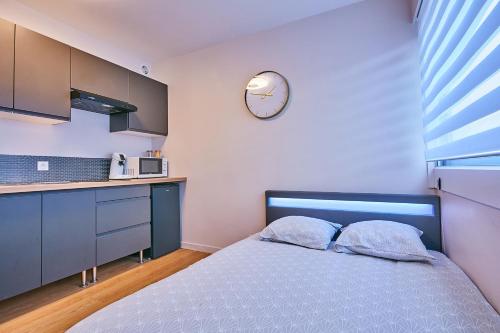 a bedroom with a bed and a clock on the wall at Studio Cosy in Pontarlier