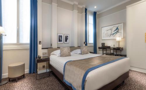 una camera da letto con un grande letto con tende blu di Hôtel Du Bois Champs-Elysées a Parigi