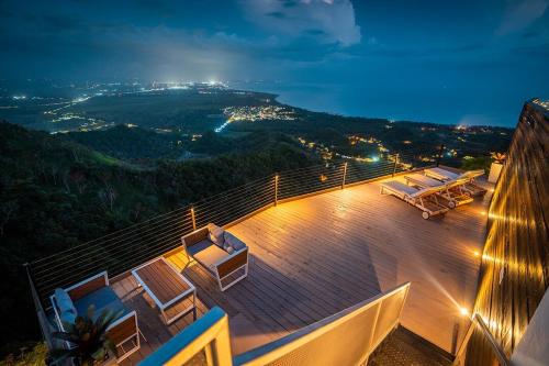 eine Terrasse mit Stühlen und Blick auf die Stadt in der Nacht in der Unterkunft Adults Only! Ocaso Luxury Villas Entire Property in Rincon