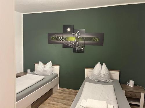two beds in a room with green walls at Gästehaus Graupner-Hainichen in Hainichen