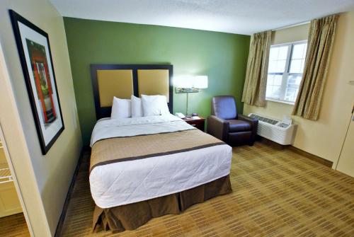 レイクウッドにあるExtended Stay America Select Suites - Denver - Lakewood Southの大きなベッドと椅子が備わるホテルルームです。
