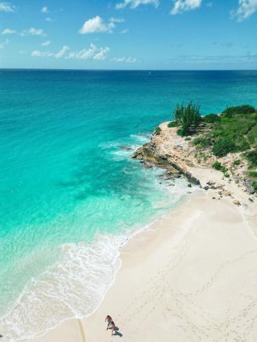 a woman walking on a beach next to the ocean at Fourteen at Mullet Bay in Cupecoy