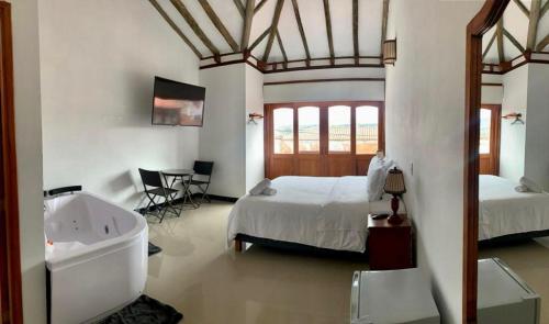 um quarto com uma cama e uma banheira ao lado de um lavatório em Hospederia Villa de los Sáenz em Villa de Leyva