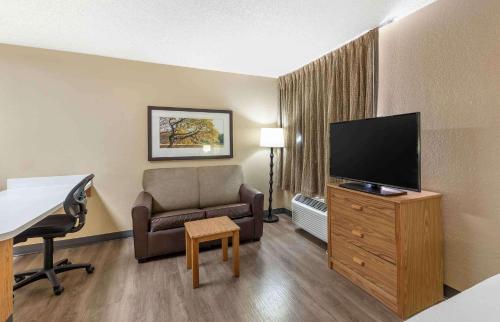 a hotel room with a chair and a flat screen tv at Extended Stay America Select Suites - Denver - Tech Center South - Greenwood Village in Centennial