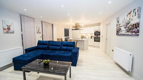 a living room with a blue couch and a table at "Easy 2 Manage Royal Penthouse Luxurious Retreat in Slough" in Slough