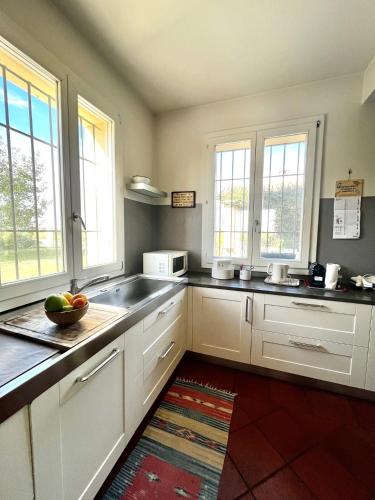 a kitchen with white cabinets and a sink and windows at Country house 15km from Bologna in Budrio