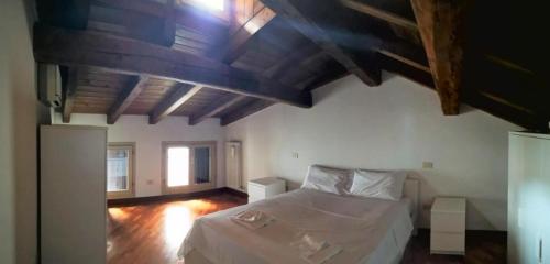 a bedroom with a white bed and a wooden ceiling at De' Pepoli Rooms & Apartments in Bologna