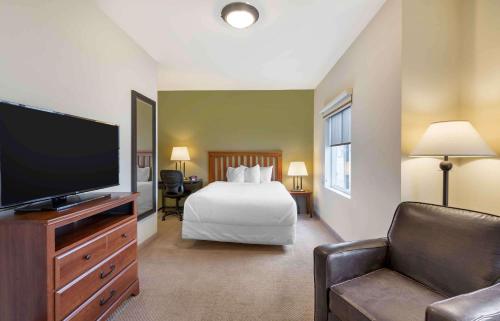 a hotel room with a bed and a flat screen tv at Extended Stay Americas Suites - Minot in Minot