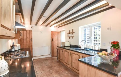 een grote keuken met houten kasten en een fruitschaal op het aanrecht bij Private Bedrooms in Quaint Oxfordshire Village Cottage in Wantage