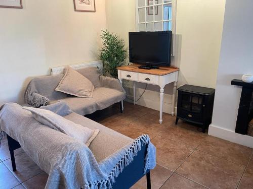 a living room with a couch and a tv at Private Bedrooms in Quaint Oxfordshire Village Cottage in Wantage