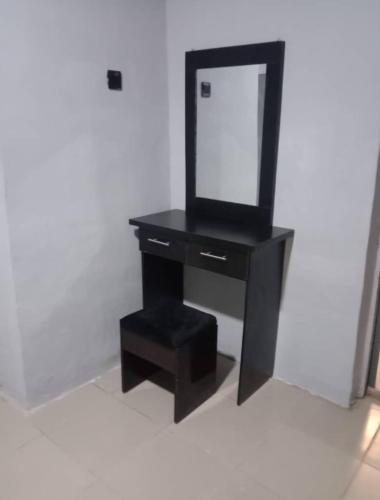 a black dressing table with a mirror and a stool at Fairways Apartments in Otta