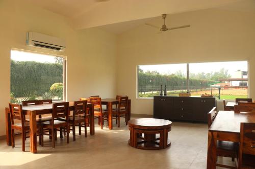 uma sala de jantar com mesas e cadeiras e uma grande janela em The Bageecha em Vrindavan