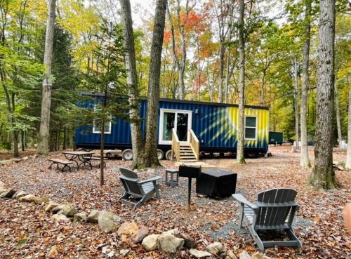 a blue and yellow tiny house in the woods at Camptel Poconos Lodging in Albrightsville