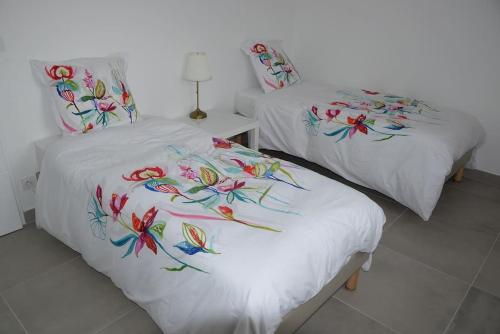 two beds with white sheets with colorful butterflies on them at Le Rouge Gorge à 12 minutes d'Eurexpo in Genas