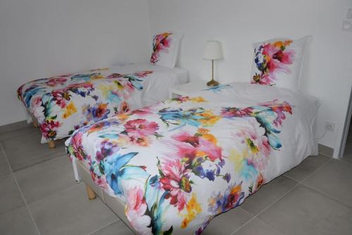 a bedroom with two beds with floral sheets at Le Rouge Gorge à 12 minutes d'Eurexpo in Genas