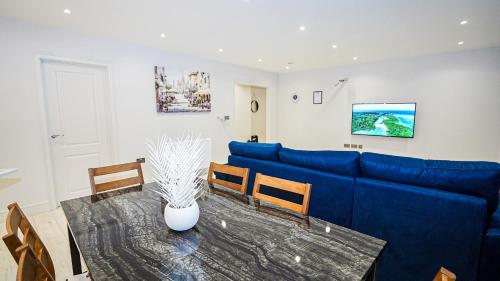 a living room with a blue couch and a table at "Easy 2 Manage Royal Penthouse Luxurious Retreat in Slough" in Slough