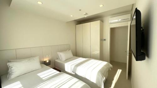 two beds in a small room with a television at Sunraf Luxe Apartments in Budva