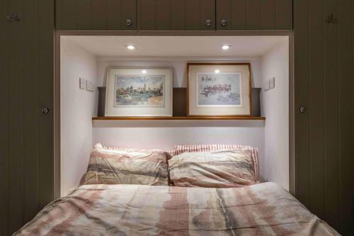a bed in a room with two pictures above it at Shared Guest House 5 mins walk from Vauxhall and Nine Elms Station with off-site parking near US embassy in London