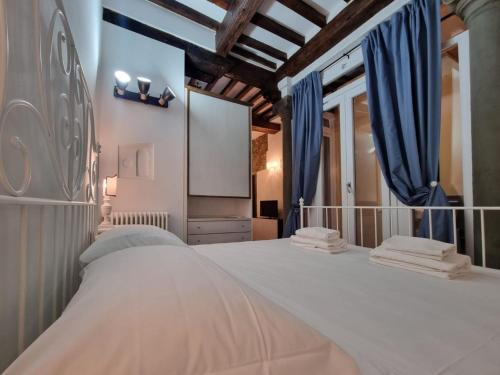 een slaapkamer met een groot wit bed en blauwe gordijnen bij Borgo Allegri Apartment in Florence