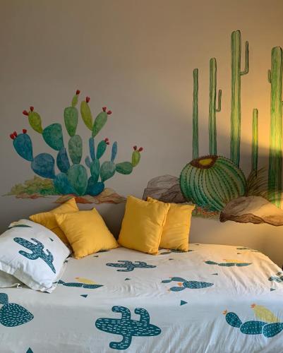 a bedroom with a bed with a cactus mural on the wall at Casa las Alas de San Miguel in San Miguel de Allende