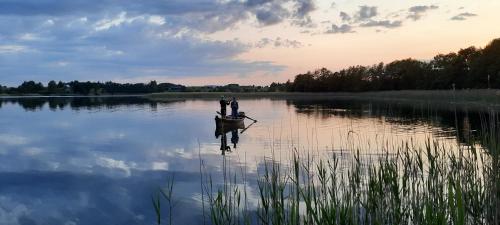 two people are standing in a boat on a lake at Dereniowe Wzgórze in Sejny