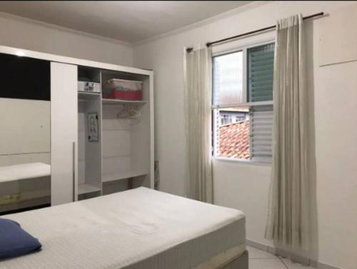 ein weißes Schlafzimmer mit einem Bett und einem Fenster in der Unterkunft Quarto em Santos - Boqueirão in Santos