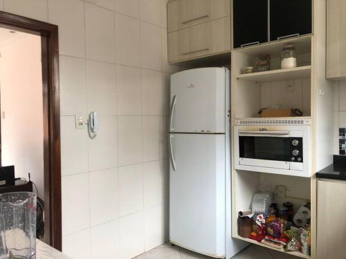 eine Küche mit einem weißen Kühlschrank und einer Mikrowelle in der Unterkunft Quarto em Santos - Boqueirão in Santos