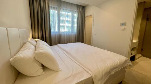 a bedroom with a white bed with pillows and a window at Sunraf Luxe Apartments in Budva