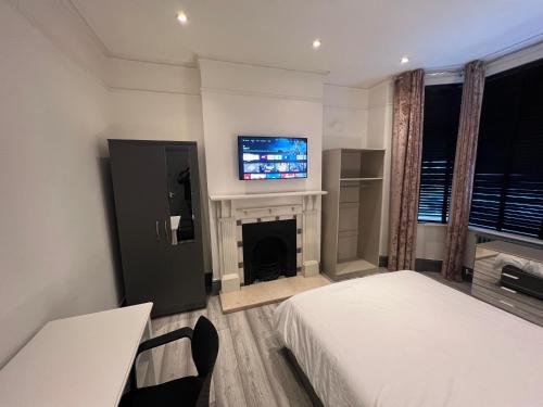 1 dormitorio con 2 camas, TV y chimenea en Rooms in Modernised Victorian House en Croydon