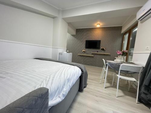 a bedroom with a bed and a table and a bathroom at Baneasa Luxury Apartaments in Bucharest