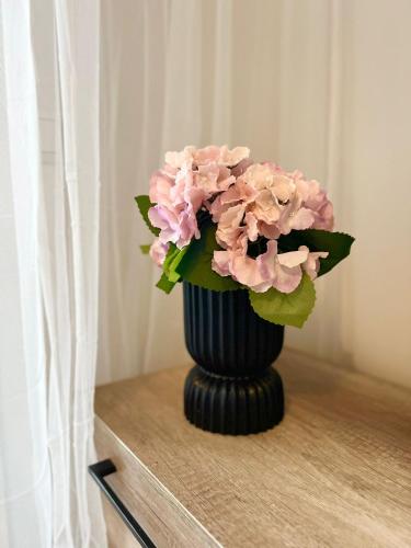 a black vase with pink flowers on a table at Star of Annala in Tampere