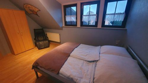 a bedroom with a bed and two windows at Ferienwohnung Hahnentange in Rhauderfehn